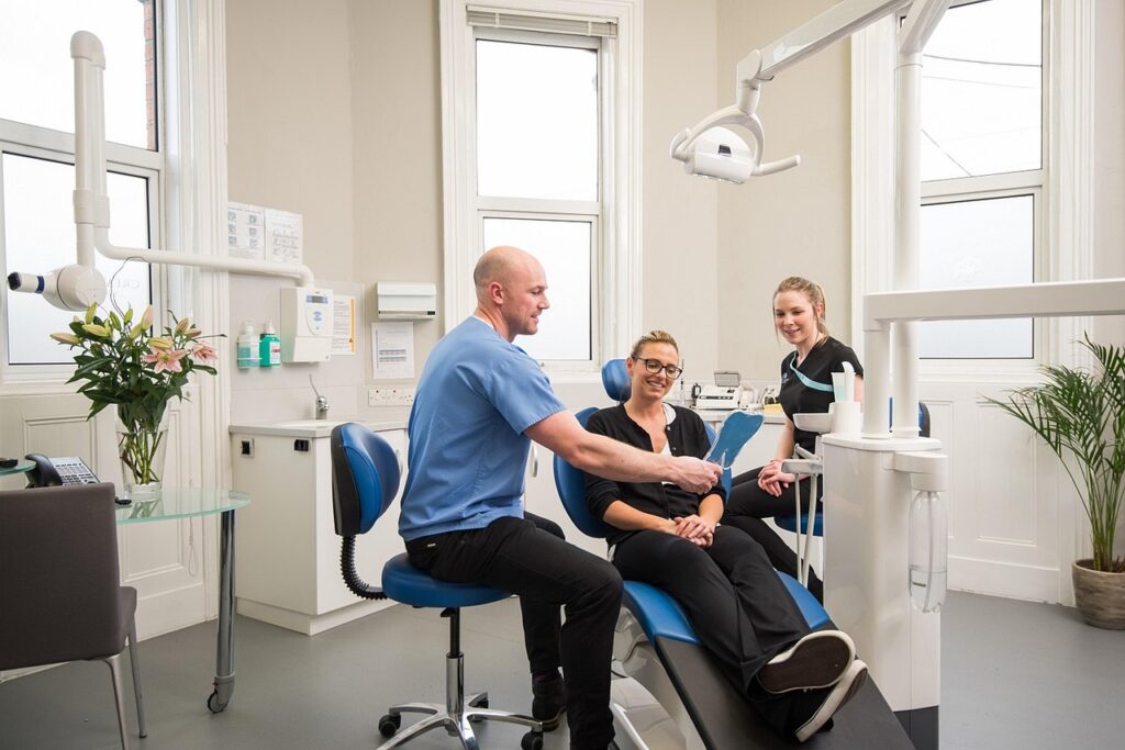Dentista mostrando resultado do tratamento de prótese protocolo para paciente sorrindo em consultório